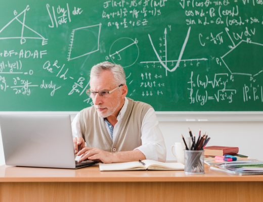 nauczyciel siedzący przy biurku pisze na klawiaturze, laptop dla nauczyciela